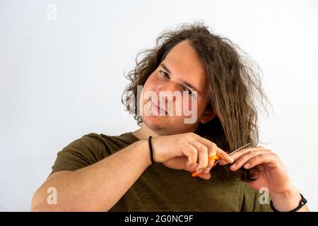 Young smiling guy is about to cuthair with scissors Stock Photo