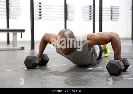 Young black man doing pushups with kettlebells on gym floor. Space for text. Stock Photo