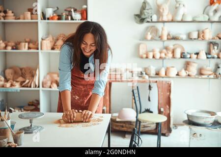 Cheerful young woman working in pottery workshop Stock Photo