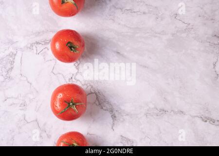 Line of tomatoes on composition on a marble table. Stock Photo