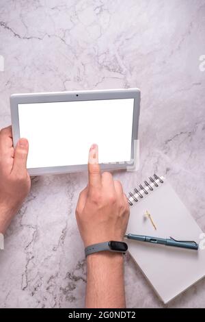 Hands of an unknown person using a tablet on a marble background. Stock Photo