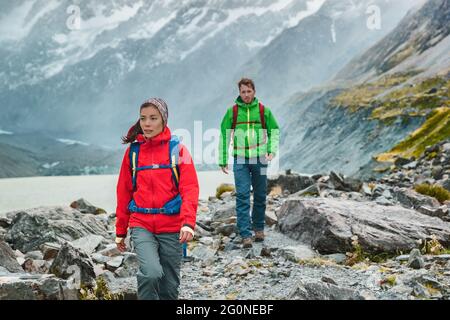 People hiking travel lifestyle. People on hike wearing backpacks in nature landscape with glacier in small icebergs in Tasman Lake on New Zealand in Stock Photo