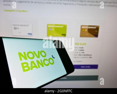 Cellphone with company logo of Portuguese bank Novo Banco S.A. on screen in front of business website. Focus on center-right of phone display. Stock Photo