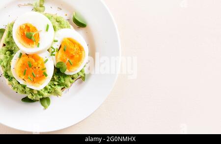 Close up view of avocado toast bun with eggs on plate over light stone background with free text space. Top view, flat lay Stock Photo