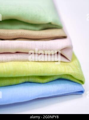 Stack of linen cloth fabrics in pastel colors. Closeup isolated colorful towels. Sewing items or tailoring objects concept. High quality vertical photo Stock Photo