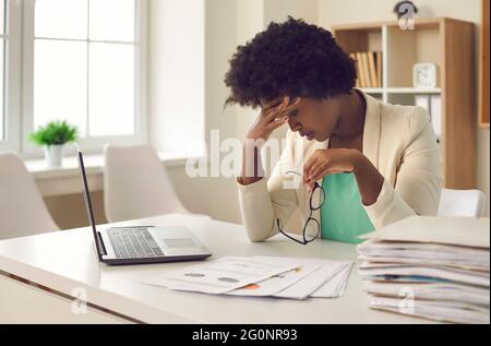 African-American business woman who is tired of work routines and deadlines suffers from headaches. Stock Photo