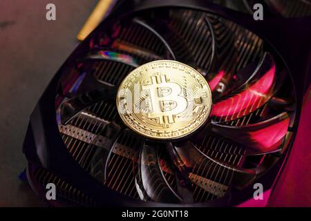 On the fans of a powerful video card, the coins of the Bitcoin cryptocurrency with a red backlight are displayed.The concept of mining and mining of c Stock Photo