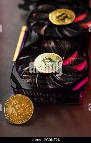 On the fans of a powerful video card, the coins of the Bitcoin cryptocurrency with a red backlight are displayed.The concept of mining and mining of c Stock Photo