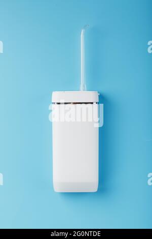 White oral irrigator on a blue background. A mobile device for brushing your teeth and a snow-white smile. Free space Stock Photo