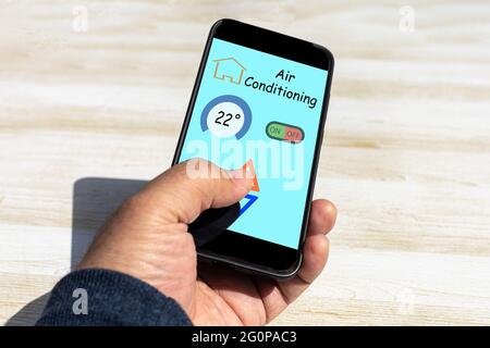 person using an application on the mobile phone to control the air conditioner at home where you see the degrees and the keys to raise and lower the t Stock Photo