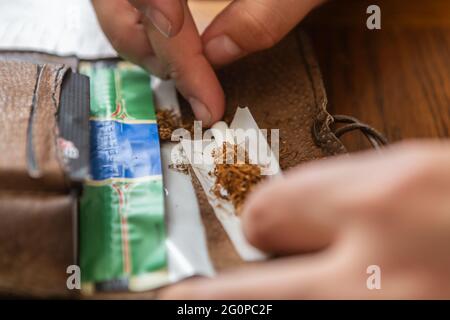 a person rolls a cigarette with tobacco Stock Photo