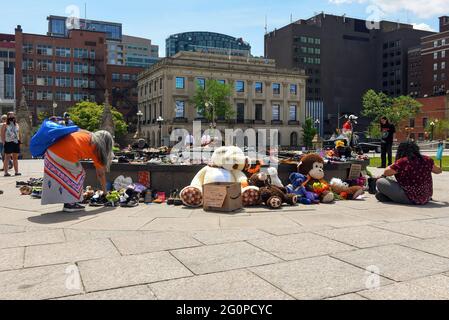 Ottawa, Canada - June 2, 2021: People gather round and leave shoes and toys left near the Centennial Flame on Parliament Hill in memory of the 215 children whose remains were found near of former Residential School in Kamloops, B.C. Stock Photo