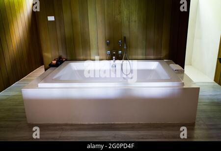 Bathroom interior decor with home spa bathtub. Modern contemporary hot tub on the dark bathroom decorated wall and floor with wood. Stock Photo