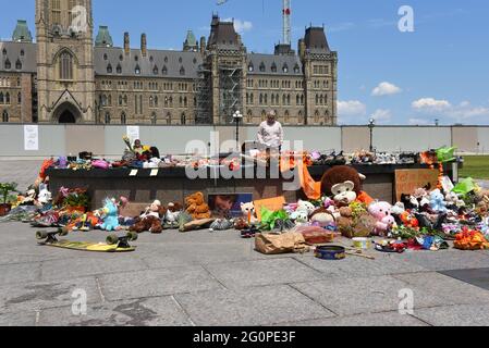 Ottawa, Canada - June 2, 2021: People gather round and leave shoes and toys left near the Centennial Flame on Parliament Hill in memory of the 215 children whose remains were found near of former Residential School in Kamloops, B.C. Stock Photo