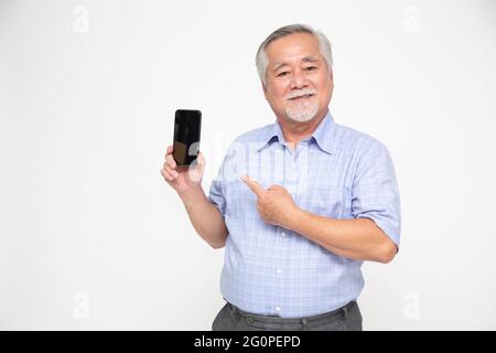 Portrait of a Asian senior man showing or presenting mobile phone application and pointing finger to smartphone on hand isolated over white background Stock Photo