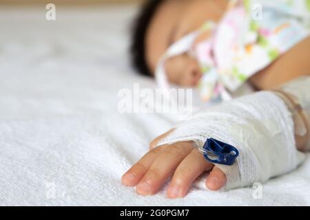 Asian baby boy sleeping on bed with infusion set at child department in the hospital. Children with infectious diseases IPD, Invasive Pneumococcal Dis Stock Photo