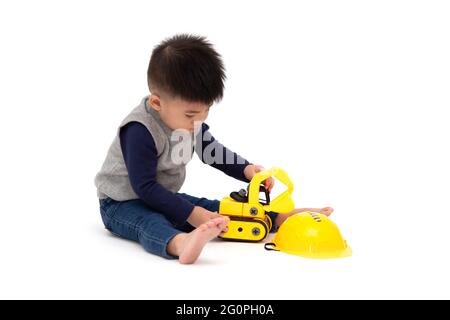 Portrait of a cute Asian little boy sitting on floor and playing car toy construction isolated on white background, 1 year 10 month old Stock Photo