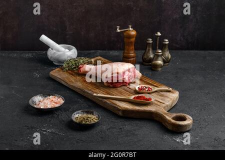 Raw turkey drumstick with skin on wooden board Stock Photo