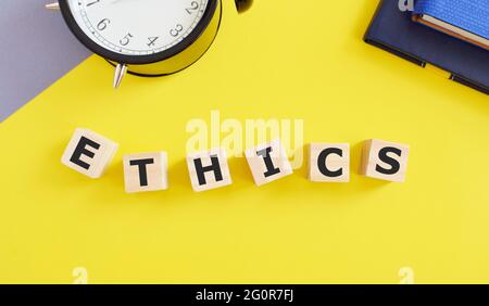 ETHICS word concept made with building blocks, yellow background. Stock Photo