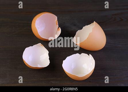 Closeup cracked eggshells isolated on dark brown wooden background Stock Photo