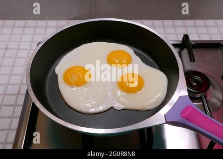 Closeup three of eggs being fried in a pan Stock Photo