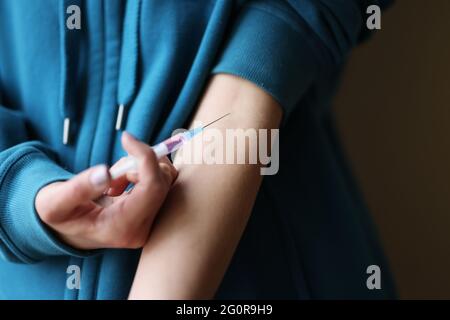 Woman addict injecting drugs into cubital vein closeup Stock Photo