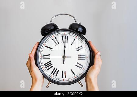 Female hand holding a big vintage alarm clock Stock Photo