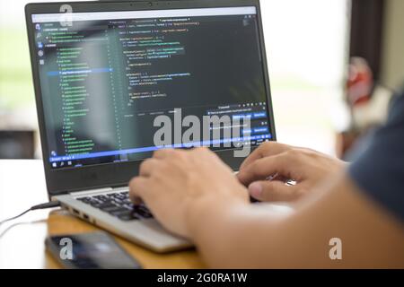 Freelance programmer or developer working at home and typing source code with laptop Stock Photo