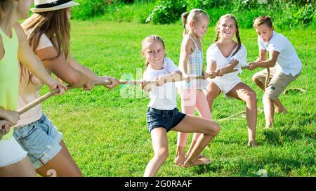 people with kids having fun outdoors pulling rope Stock Photo