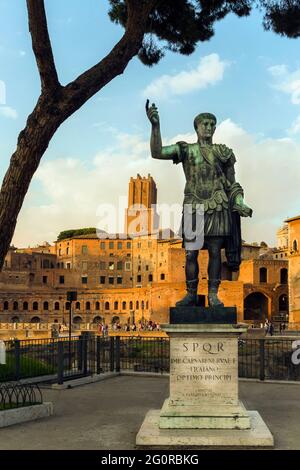 Rome, Italy.   Statue of the Emperor Trajan with Trajan's Forum behind.  The forum dates from the second century AD.   The tower, centre, is the 13th Stock Photo