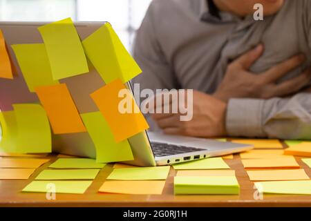 Businessman planning task work with sticky note on table in the office and having heart attack or heart failure while work hard. illness concept Stock Photo