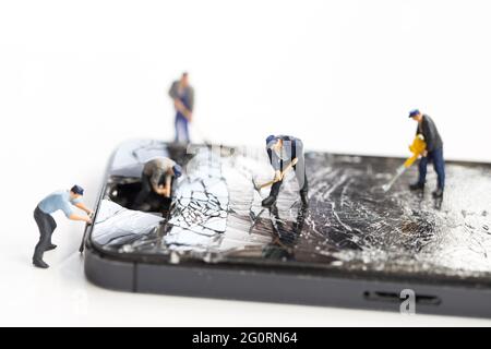 Mini technicians repairing broken screen phones caused by falling, Smartphone hitting the street and maintenance cracked mobile phone Stock Photo