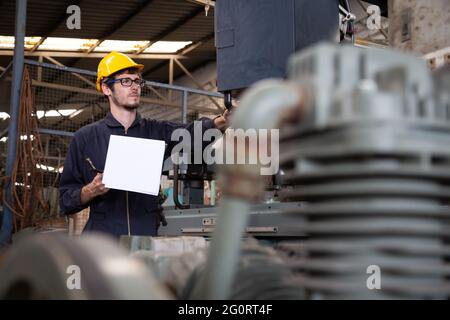 Factory engineer wearing yellow hard hat and checking the machine, Annual maintenance concept Stock Photo