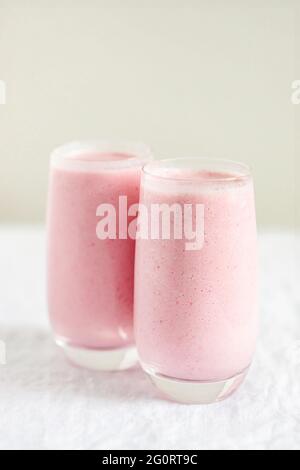 Two glasses of strawberry milkshake on table. Stock Photo