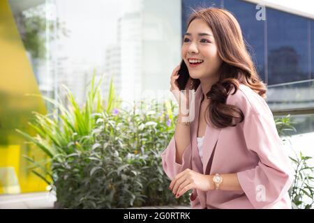 Attractive Asian businesswoman talking on mobile phone with client Stock Photo