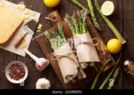 Fresh green asparagus with parmesan cheese, lemon and spices on rustic wooden planks Stock Photo