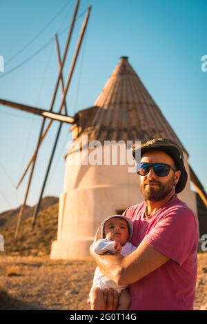 Young father with his newborn son enjoying a vacation in San Jose, Spain with mills in background Stock Photo