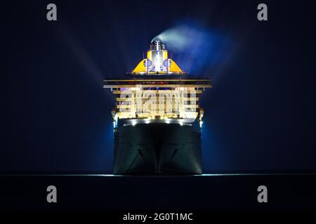 The magnificent Queen Mary 2 ocean liner cruise ship is illuminated at night whilst anchored off Torbay in Devon, UK. Stock Photo