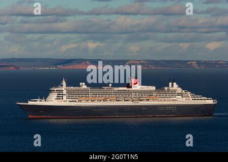 The magnificent Queen Mary 2 ocean liner cruise ship sits on calm seas whilst anchored off Torbay in Devon, UK. Stock Photo