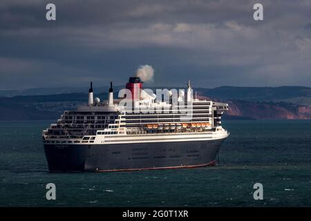 The magnificent Queen Mary 2 ocean liner cruise ship sits on choppy seas whilst anchored off Torbay in Devon, UK. Stock Photo