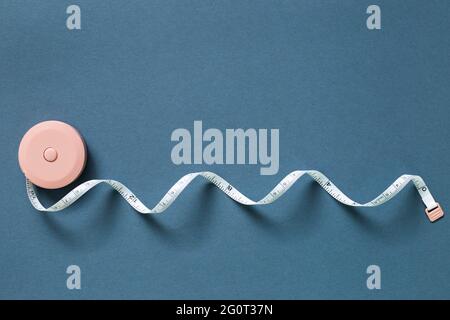 Pink tape measure on navy blue background. top view, copy space Stock Photo