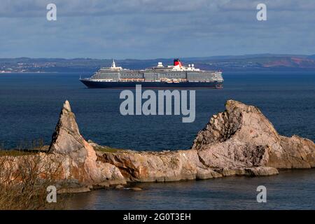 The Queen Victoria cruise ship sits on calm waters near Anstey's Cove whilst anchored off Torbay in Devon, UK.
