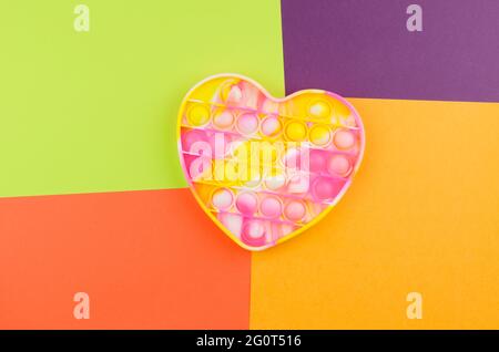 Bright colored toy Pop it fidget on a colored background. Children's toy for the development of fine motor skills. Stock Photo