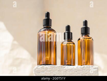 Natural hyaluronic serum in bottles with a pipette on a white podium on a beige background. Natural essential oil or serum on the advertising podium. Stock Photo
