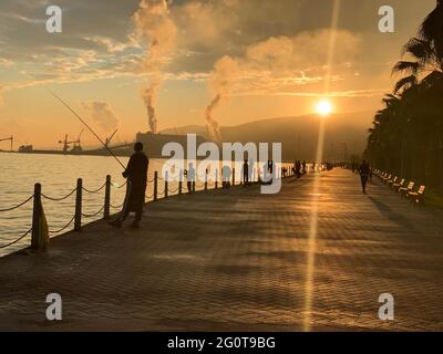 People fishing with a hook by the sea, polluting smoke coming out of the factory chimney in the background, 2 June 2021, gulf Kocaeli Stock Photo