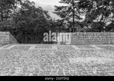 Fence and staircase made of granite stones. A cobbled area with a stone cobblestone fence. Observation deck in the city park. Black and white photo Stock Photo