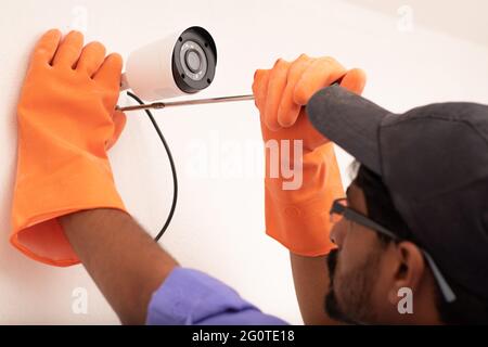 Shoulder shot of Electric Technician man setup cctv camera security system on wall - Electrician installing video surveillance camera Stock Photo