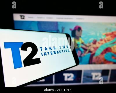 Cellphone with logo of video game company Take-Two Interactive Software Inc. on screen in front of website. Focus on center-left of phone display. Stock Photo