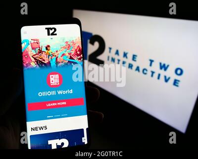 Person holding smartphone with website of video game company Take-Two Interactive Software Inc on screen with logo. Focus on center of phone display. Stock Photo