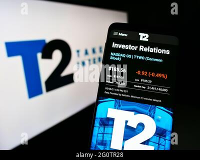 Person holding mobile phone with webpage of video game company Take-Two Interactive Software on screen with logo. Focus on center of phone display. Stock Photo